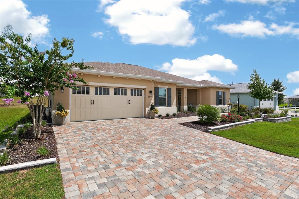 A single-story house with a tan stucco exterior, a paver driveway, and a two-car garage — 9707 SW 103RD TERRACE, OCALA, FL