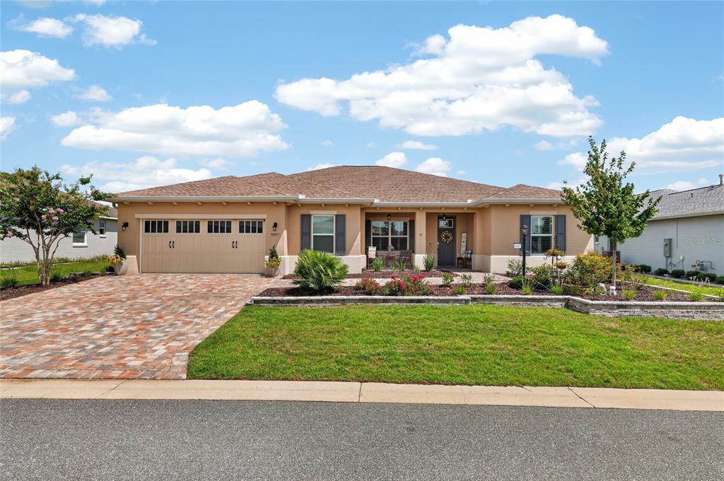 A single-story house with a tan stucco exterior, a paver driveway, and a landscaped front yard — 9707 SW 103RD TERRACE, OCALA, FL