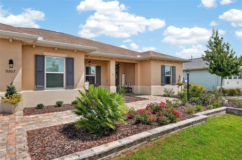 A single-story house features a tan stucco exterior, dark shutters, and a stone-paved walkway — 9707 SW 103RD TERRACE, OCALA, FL