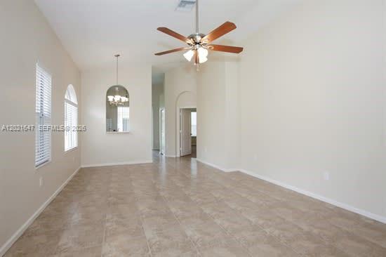 A spacious living area features light-colored walls, tile flooring, and a ceiling fan — HOMESTEAD, FL