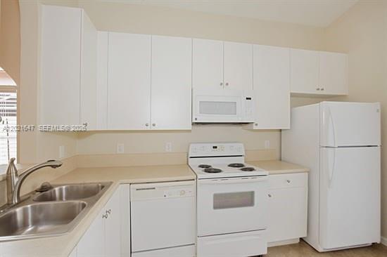A kitchen features white cabinets, white appliances, a double sink, and light-colored countertops — HOMESTEAD, FL