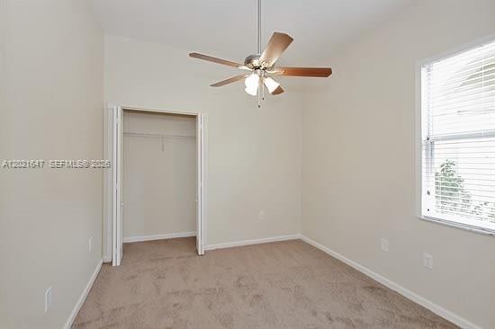 An empty bedroom with beige carpet, a ceiling fan, and a closet with bifold doors — HOMESTEAD, FL