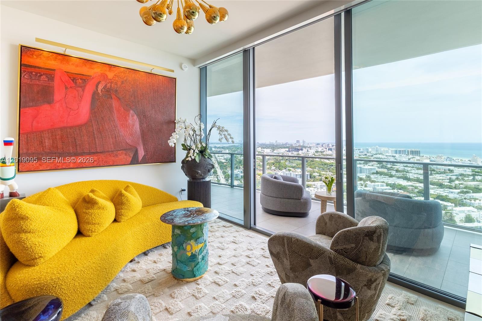 A modern living room features a yellow sofa, patterned armchairs, and a balcony with city views — 501 West Ave # 3404, Miami Beach FL 33139, MIAMI BEACH, FL