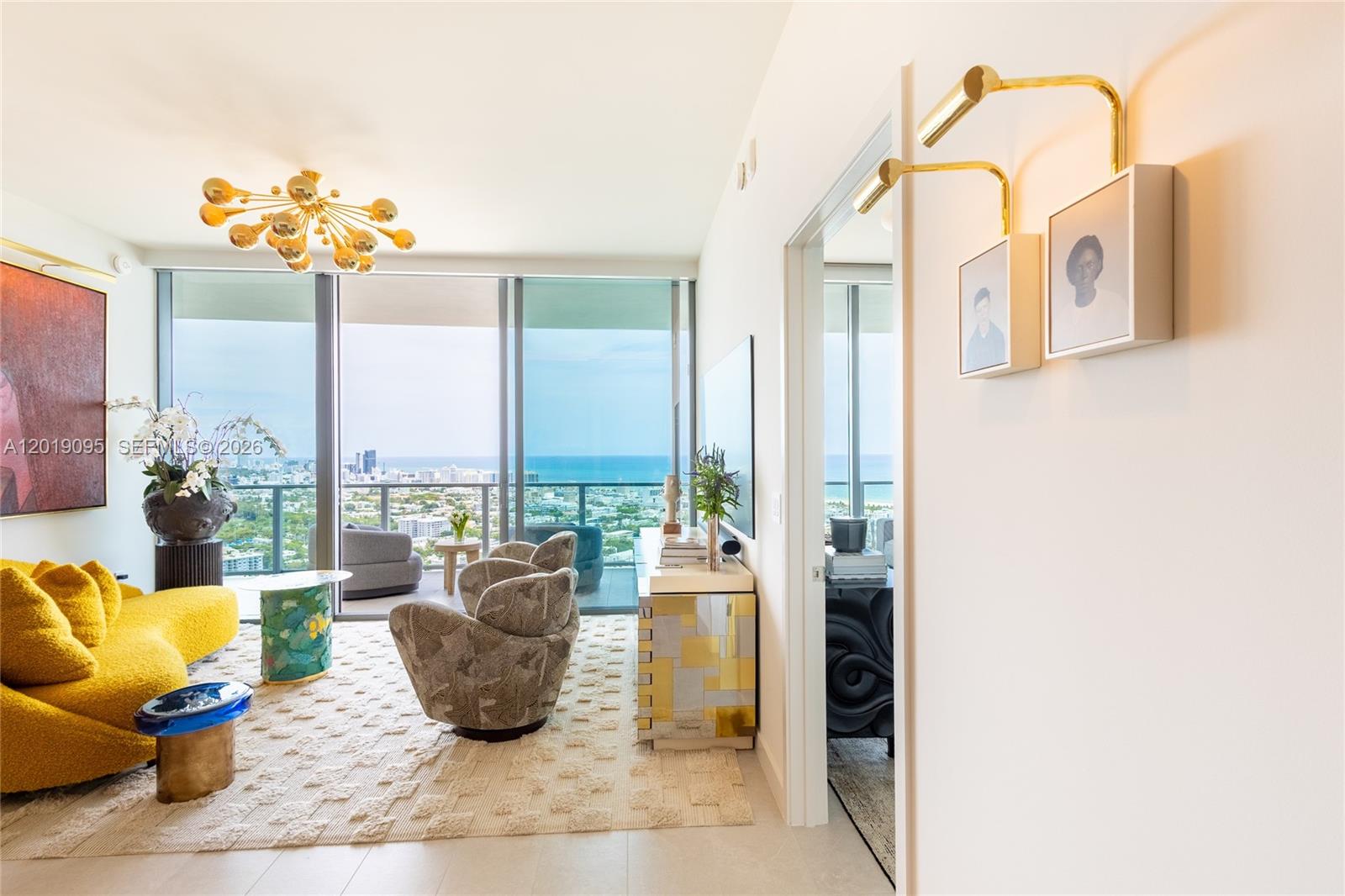 A modern living room features a yellow sofa, patterned armchairs, and floor-to-ceiling ocean views — 501 West Ave # 3404, Miami Beach FL 33139, MIAMI BEACH, FL