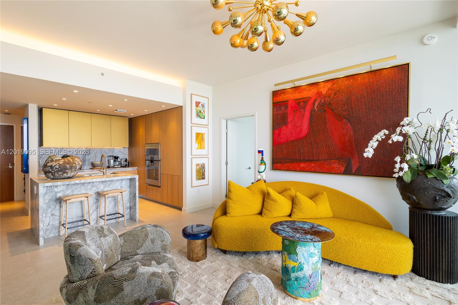 A modern living room features a yellow curved sofa, patterned armchairs, and a large painting — 501 West Ave # 3404, Miami Beach FL 33139, MIAMI BEACH, FL