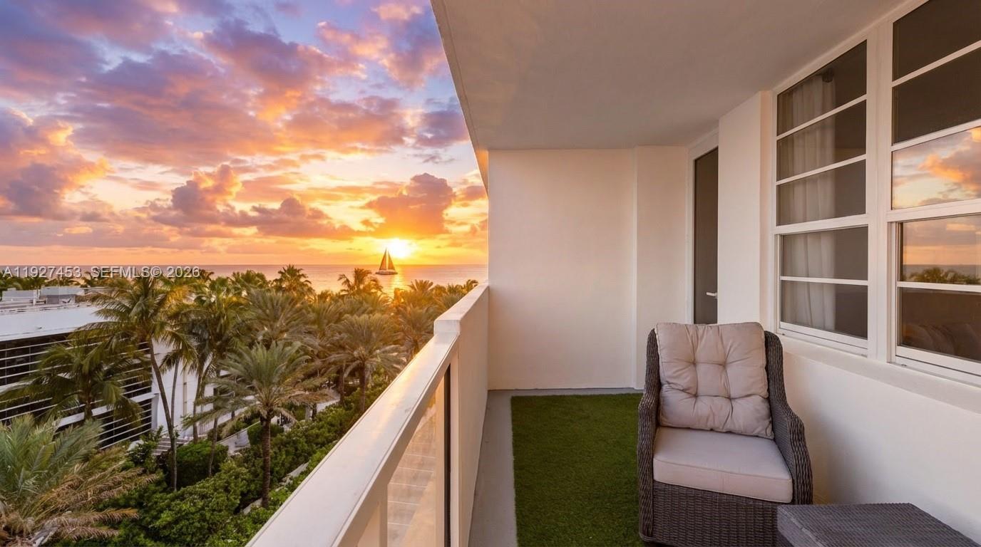 A balcony with a wicker chair, artificial turf, and a sunset view of the ocean — 100 Lincoln Rd # 643, Miami Beach FL 33139, MIAMI BEACH, FL