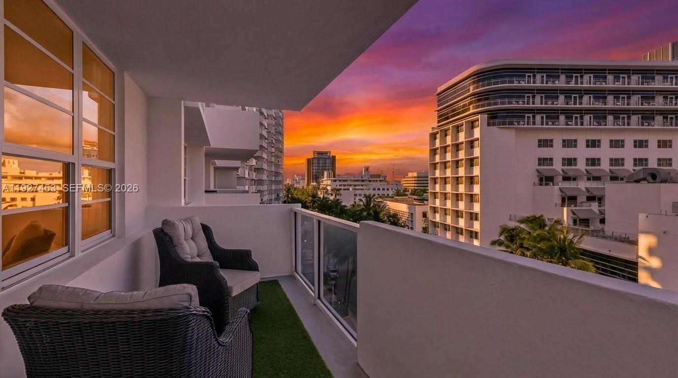 A balcony with two wicker chairs overlooks a city street at sunset — 100 Lincoln Rd # 643, Miami Beach FL 33139, MIAMI BEACH, FL