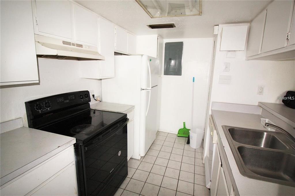 A kitchen features white cabinets, a black stove, a white refrigerator, and a double sink — 2117 LYME BAY DRIVE UNIT 604, ORLANDO, FL
