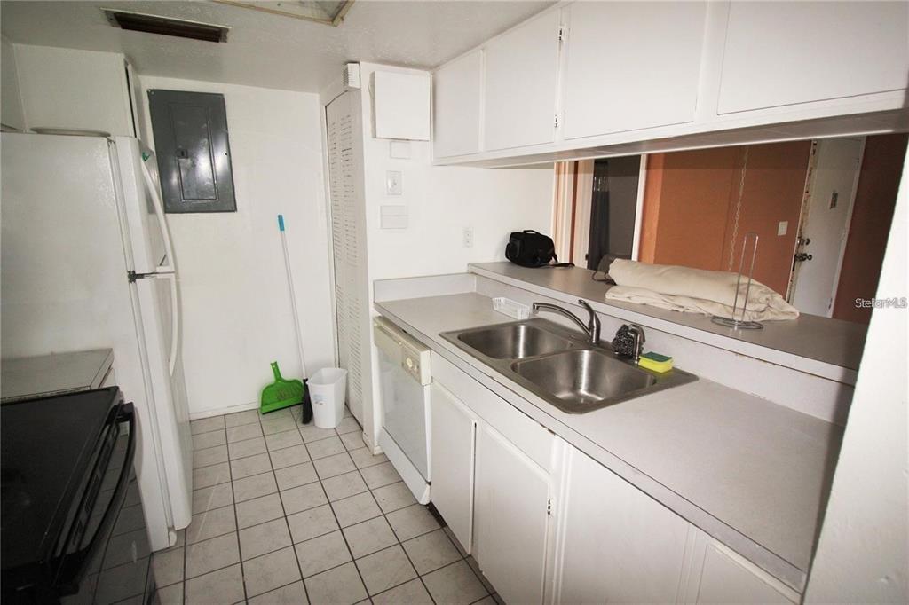 A kitchen features white cabinets, a double-basin sink, tile flooring, and a white refrigerator — 2117 LYME BAY DRIVE UNIT 604, ORLANDO, FL