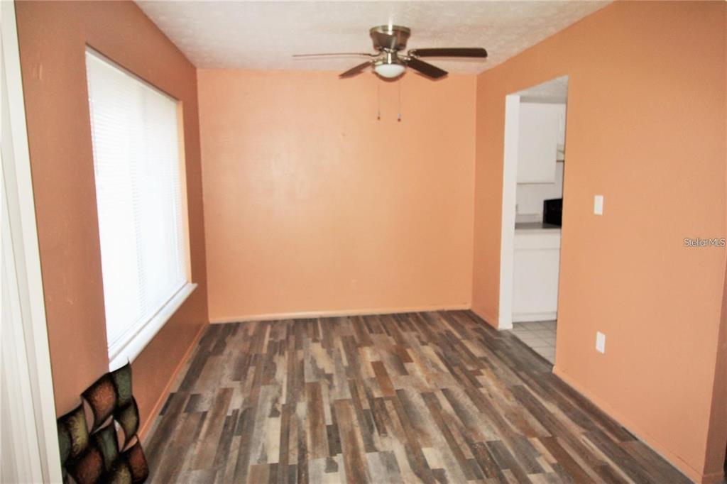 A dining room with orange walls, wood-look flooring, a ceiling fan, and a window — 2117 LYME BAY DRIVE UNIT 604, ORLANDO, FL