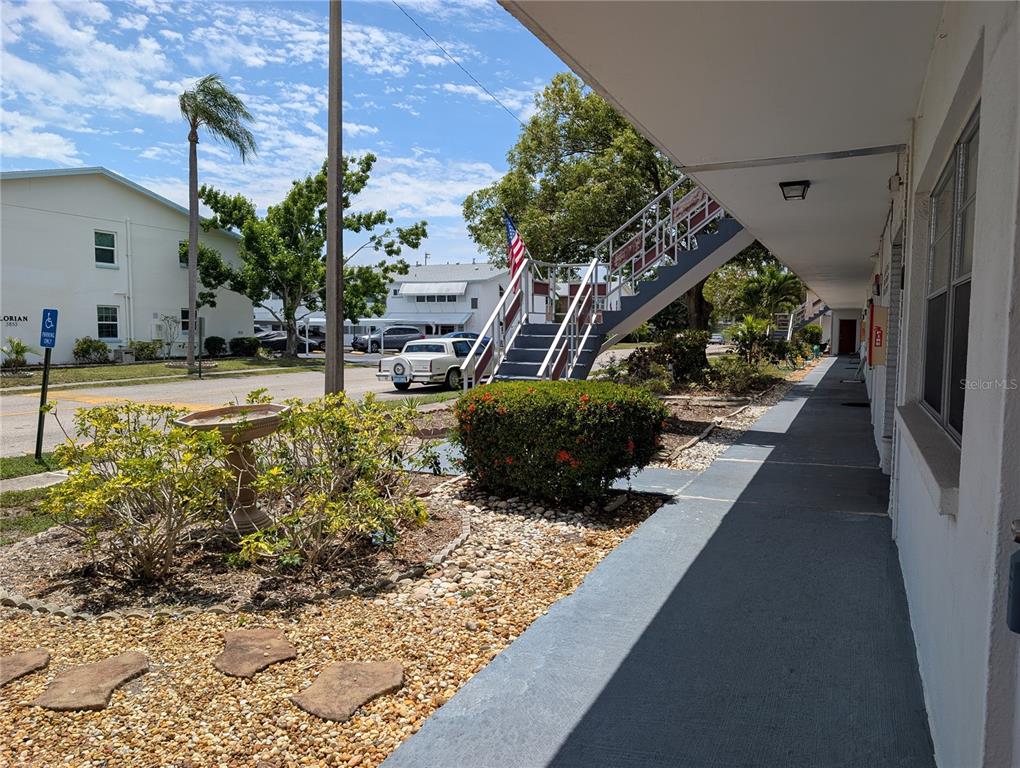 An exterior view shows a covered walkway, a staircase, landscaping, and a parking lot — 5850 18TH STREET N UNIT 7, ST PETERSBURG, FL