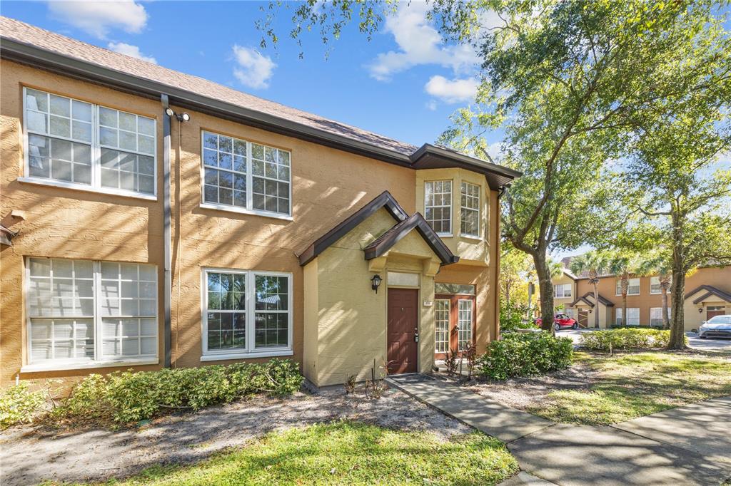 A two-story tan stucco townhouse with a brown front door and a small covered entryway — 6340 RALEIGH STREET UNIT 1011, ORLANDO, FL