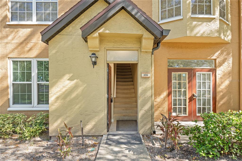 The exterior of a tan building features a central staircase entrance labeled 1011 — 6340 RALEIGH STREET UNIT 1011, ORLANDO, FL