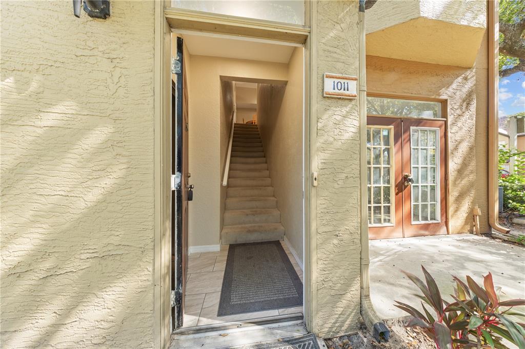 An exterior view of a building entrance with a staircase leading to an upper level — 6340 RALEIGH STREET UNIT 1011, ORLANDO, FL