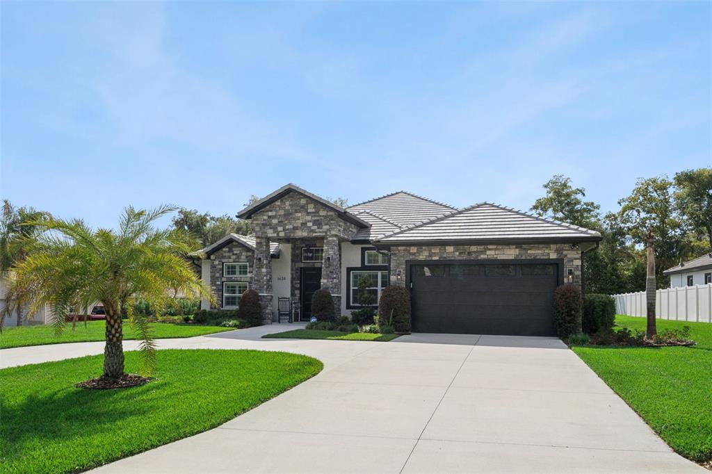A one-story house with a stone facade, a dark garage door, and a concrete driveway — 1620 BOWMAN STREET, CLERMONT, FL