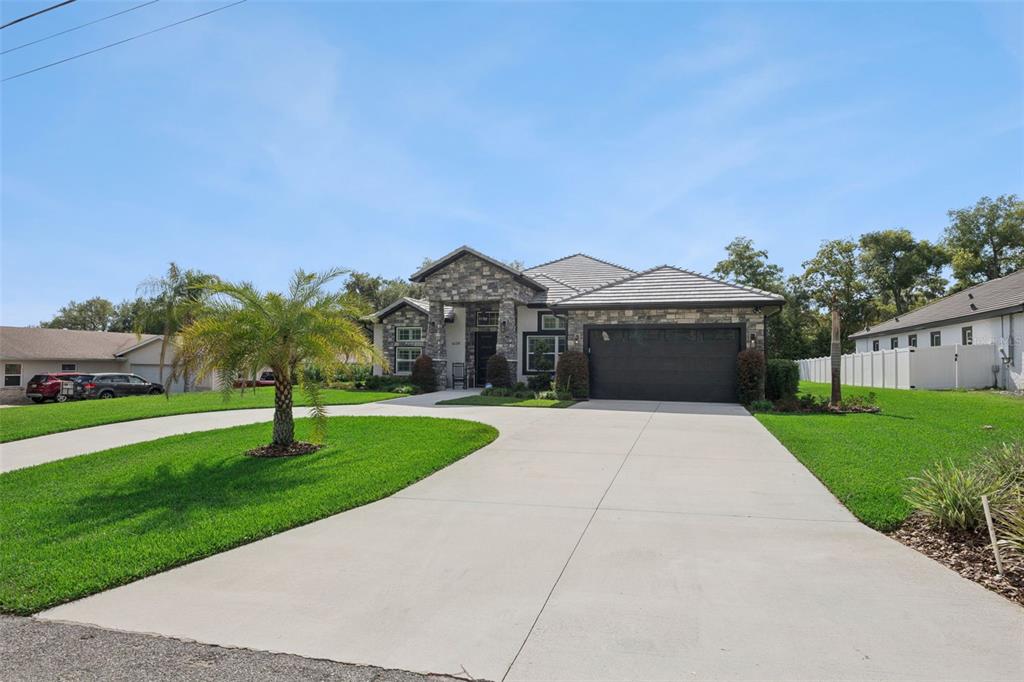 A single-story house with a stone facade, a dark garage door, and a concrete driveway — 1620 BOWMAN STREET, CLERMONT, FL