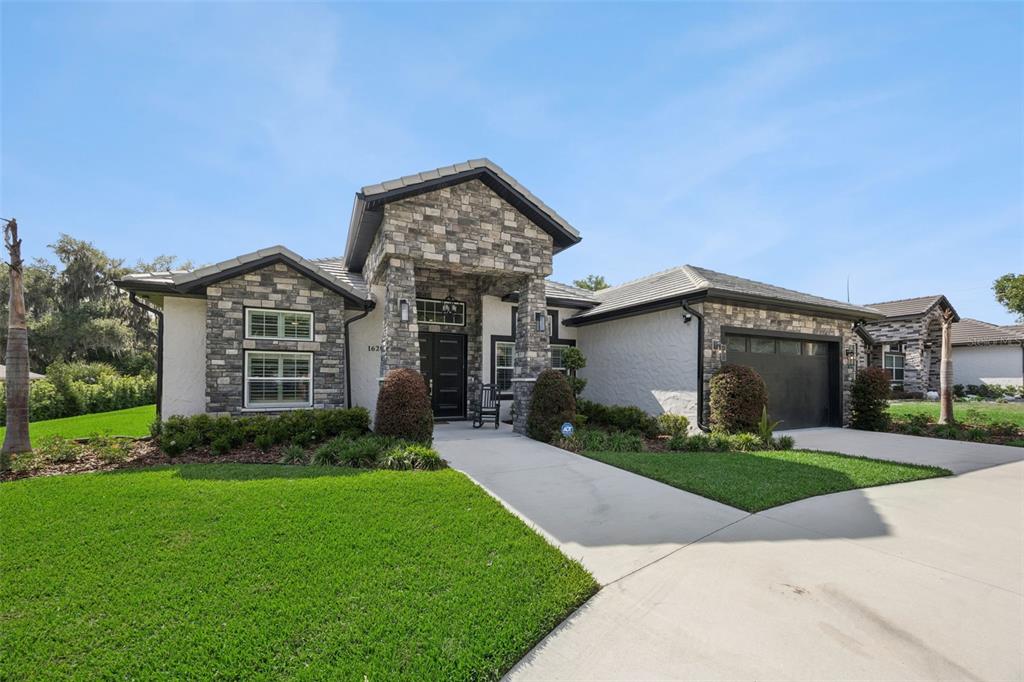 A single-story house with a stone facade, a dark garage door, and a manicured lawn — 1620 BOWMAN STREET, CLERMONT, FL