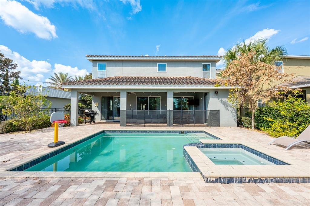 A two-story house exterior features a backyard swimming pool, hot tub, and paved patio — 111 LASSO DRIVE, KISSIMMEE, FL