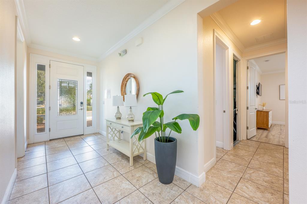 A bright entryway features tile flooring, a white front door, a console table, and a plant — 111 LASSO DRIVE, KISSIMMEE, FL
