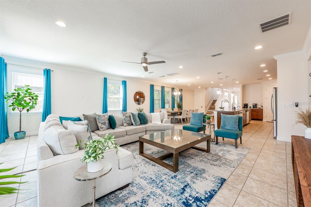 An open-concept living room features a large sectional sofa, a glass coffee table, and tile flooring — 111 LASSO DRIVE, KISSIMMEE, FL