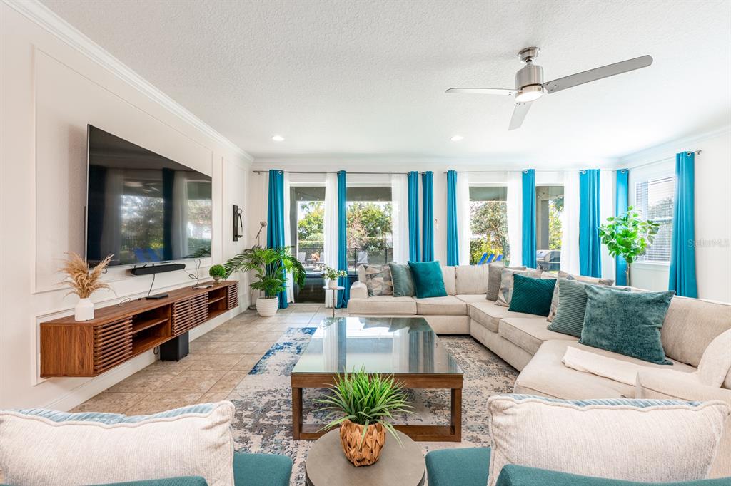 A bright living room features a large sectional sofa, a glass coffee table, and a television — 111 LASSO DRIVE, KISSIMMEE, FL