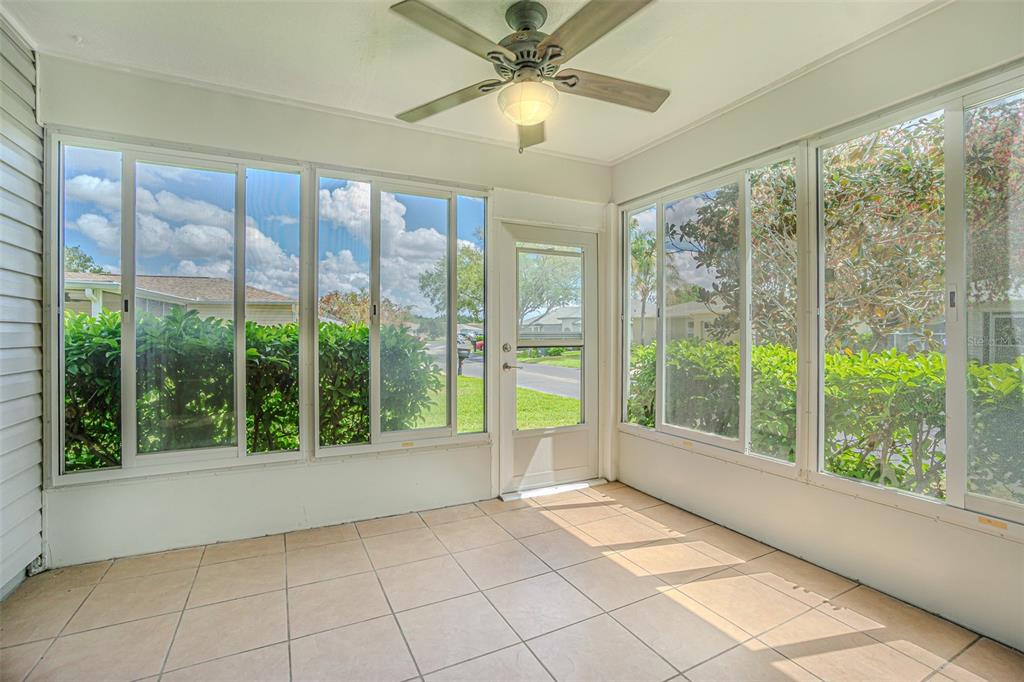 A sunroom with tiled flooring, a ceiling fan, and large windows overlooking a residential street — 11204 COREY PAVIN LANE, SAN ANTONIO, FL
