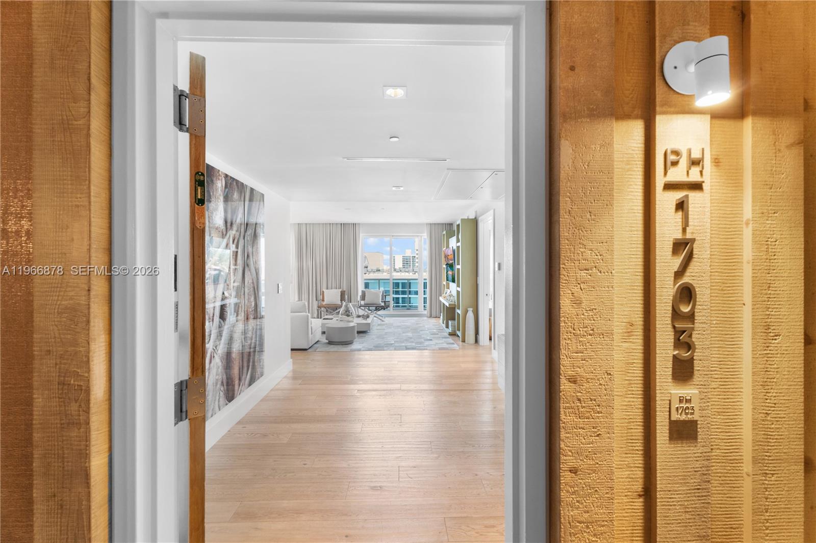 A view through an open doorway into a bright living room with hardwood floors — 102 24th St # 1703, Miami Beach FL 33139, MIAMI BEACH, FL