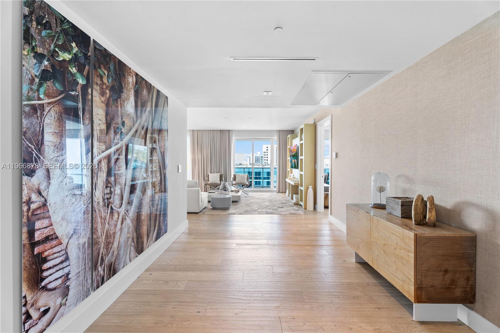 A hallway with wood flooring leads to a living area with floor-to-ceiling windows — 102 24th St # 1703, Miami Beach FL 33139, MIAMI BEACH, FL