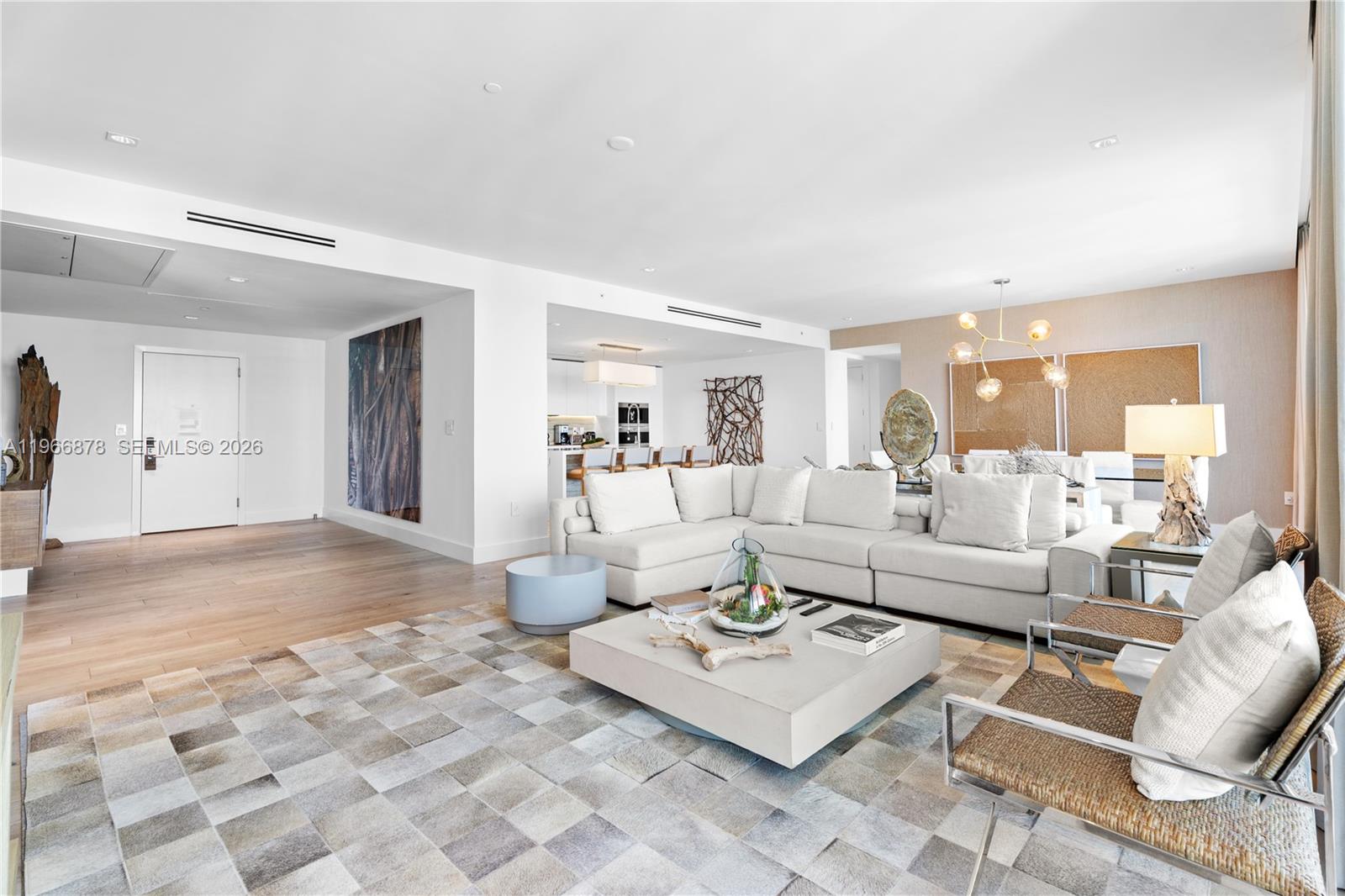A bright, open-concept living room features a large white sectional, a square coffee table, and wood flooring — 102 24th St # 1703, Miami Beach FL 33139, MIAMI BEACH, FL