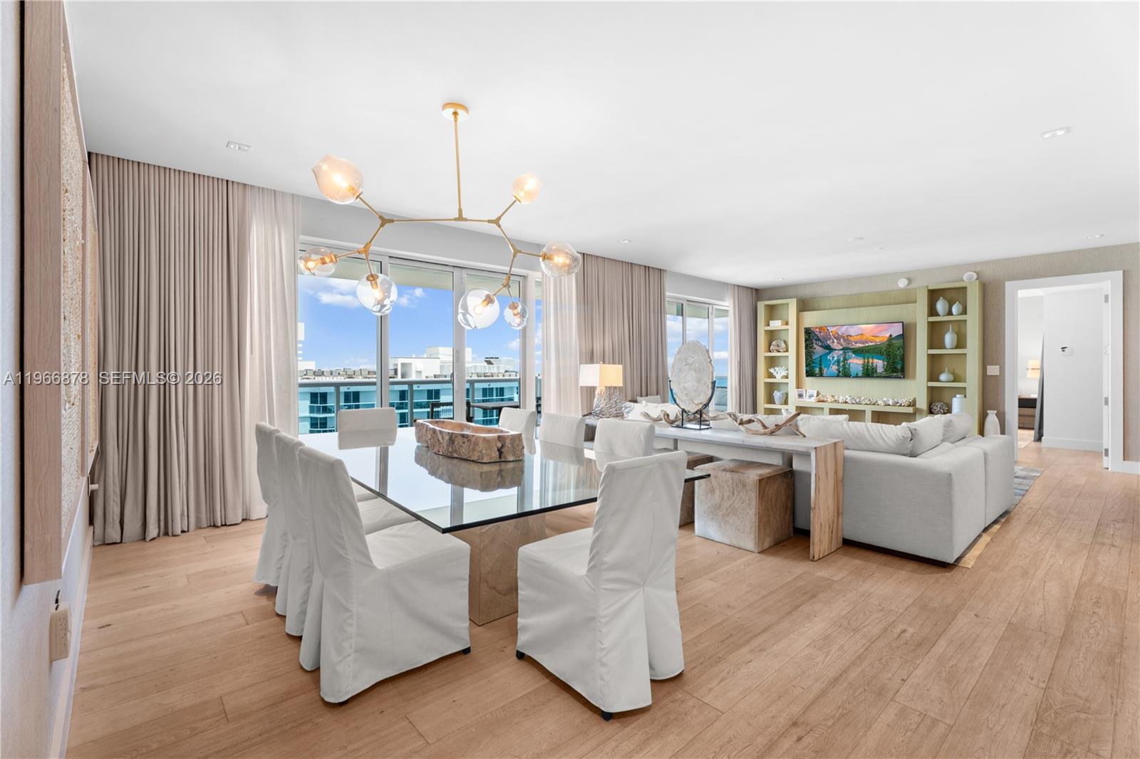 A dining area with a glass table and white chairs sits before a living room — 102 24th St # 1703, Miami Beach FL 33139, MIAMI BEACH, FL
