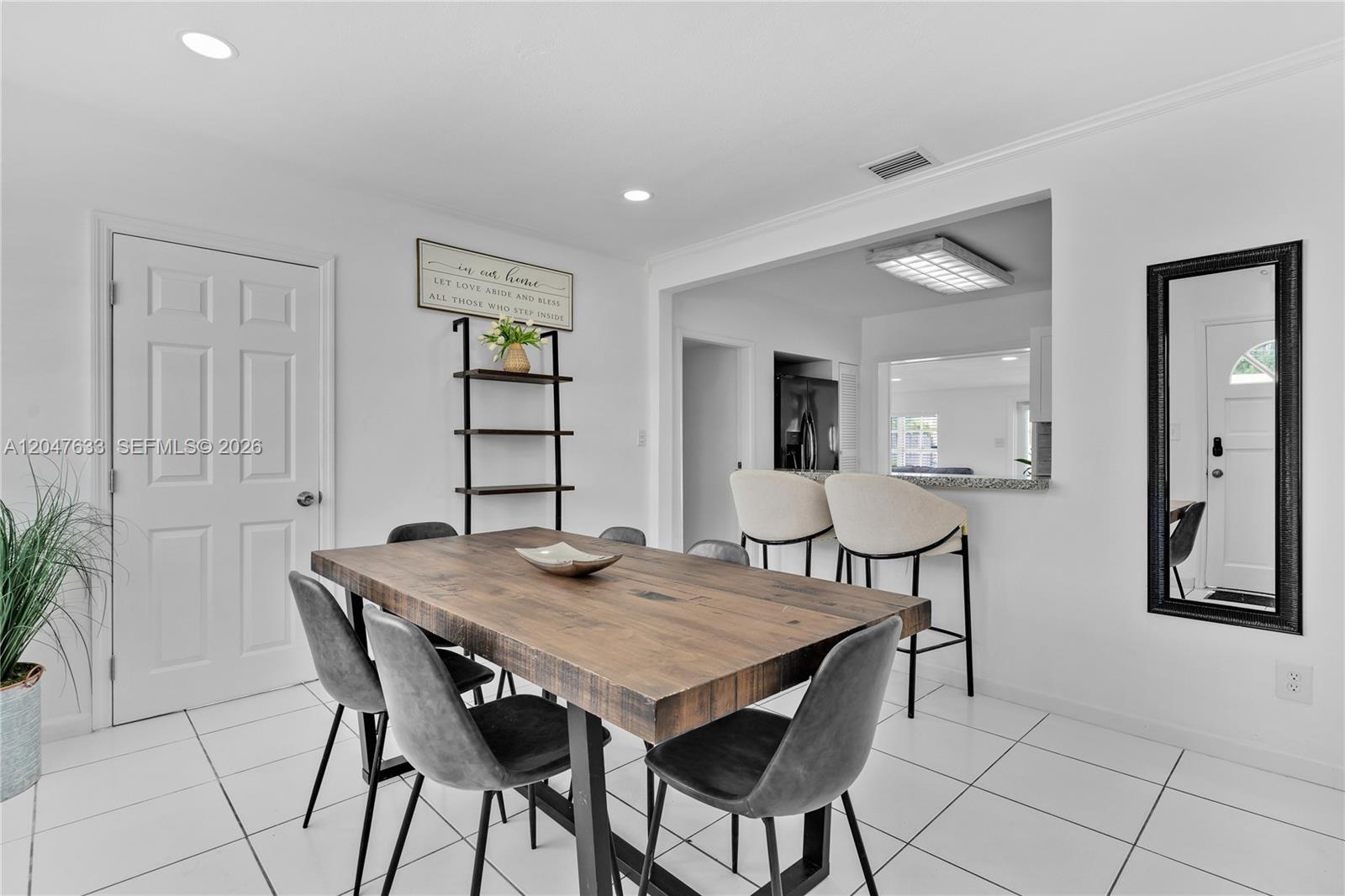 A dining area features a wooden table, gray chairs, and a breakfast bar with stools — 6445 SW 22nd Ct, Miramar FL 33023, MIRAMAR, FL