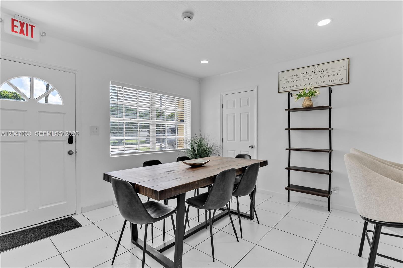 A dining room features a wooden table, dark chairs, white tile floors, and a ladder shelf — 6445 SW 22nd Ct, Miramar FL 33023, MIRAMAR, FL