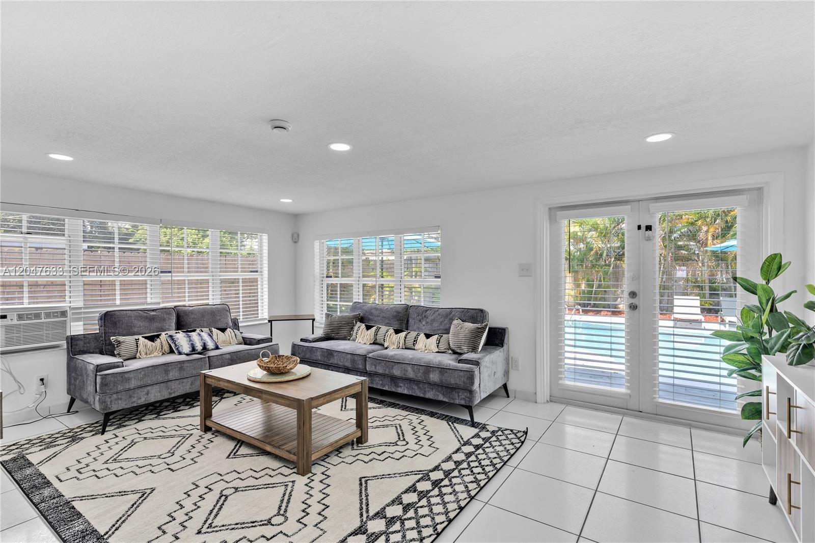 A living room features two gray sofas, a patterned rug, and glass doors overlooking a pool — 6445 SW 22nd Ct, Miramar FL 33023, MIRAMAR, FL