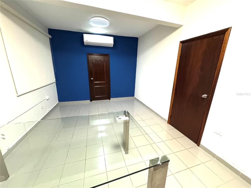 An office room features a blue accent wall, tile flooring, a glass desk, and two doors — #339 COLL Y TOSTE, SAN JUAN, PR