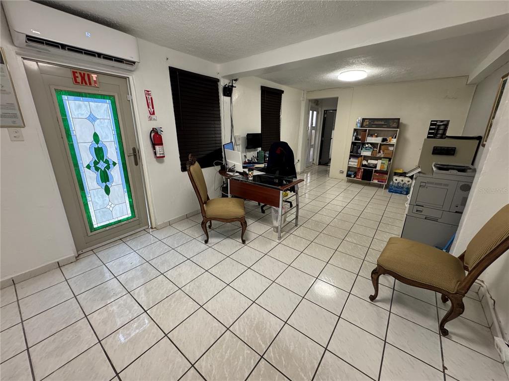 An office space features white tiled floors, a desk, two chairs, and a glass-paneled exit door — #339 COLL Y TOSTE, SAN JUAN, PR