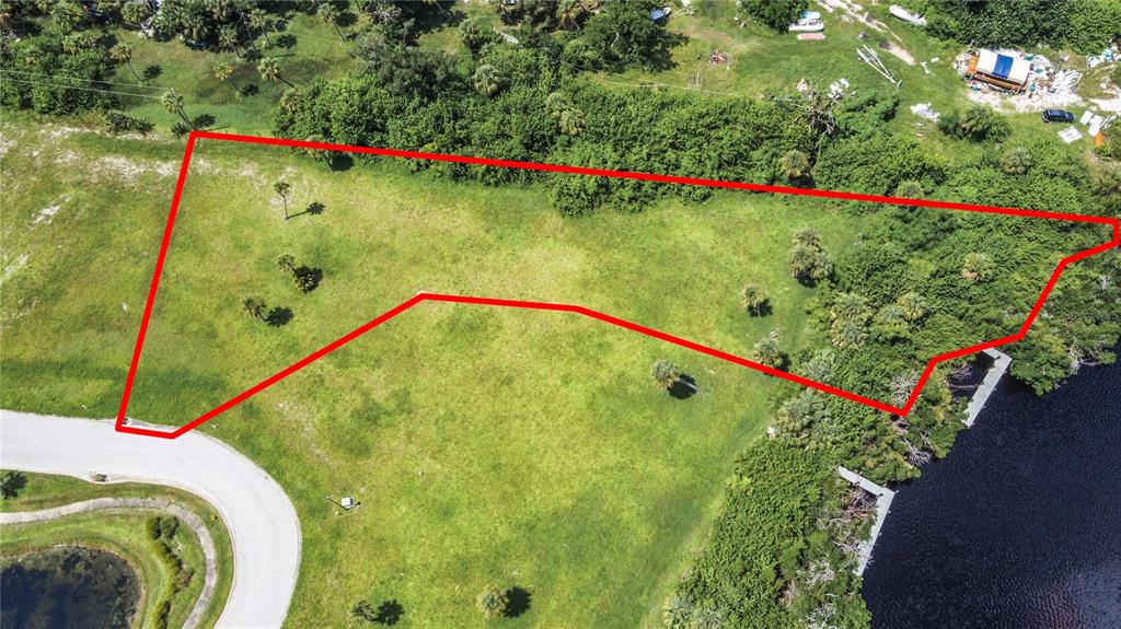 An aerial view shows a vacant, irregularly shaped grassy lot outlined in red near water — 12411 CORAL VISTA CIRCLE, PLACIDA, FL