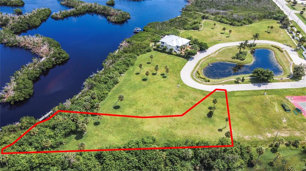 An aerial view shows a grassy lot outlined in red next to a waterfront house — 12411 CORAL VISTA CIRCLE, PLACIDA, FL