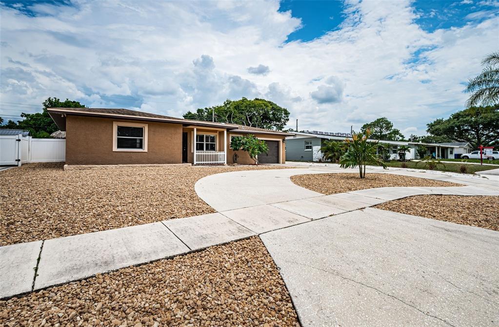 A brown single-story house features a gravel front yard and a curved concrete driveway — 1039 MADISON STREET, LARGO, FL