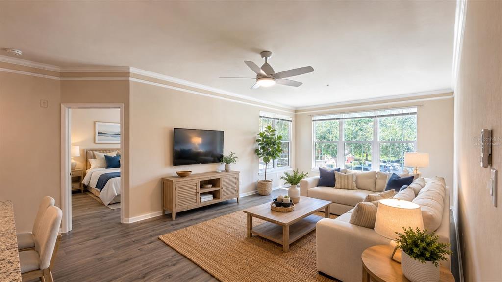 A living room with a beige sectional sofa, wood coffee table, and television on a console — 4142 CENTRAL SARASOTA PARKWAY UNIT 1423, SARASOTA, FL