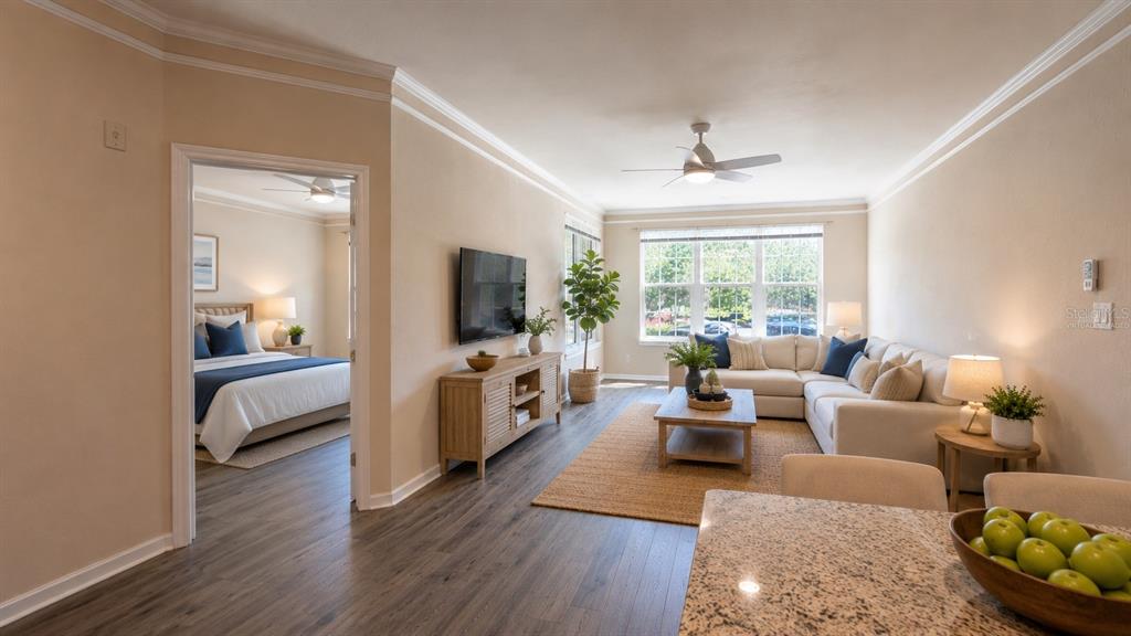 A living room with a sectional sofa, wooden media console, and an adjacent bedroom doorway — 4142 CENTRAL SARASOTA PARKWAY UNIT 1423, SARASOTA, FL