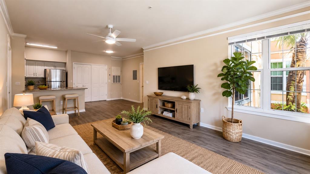 A living room with a sofa, coffee table, television, and an open kitchen with bar seating — 4142 CENTRAL SARASOTA PARKWAY UNIT 1423, SARASOTA, FL