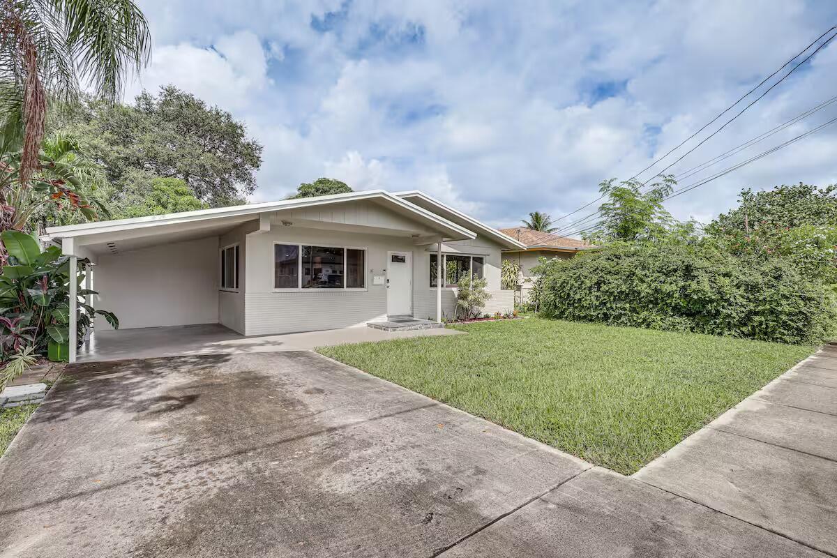A single-story house with a carport, concrete driveway, and a front lawn under a cloudy sky — 124 SW 2nd Avenue, Hallandale Beach FL 33009, HALLANDALE BEACH, FL