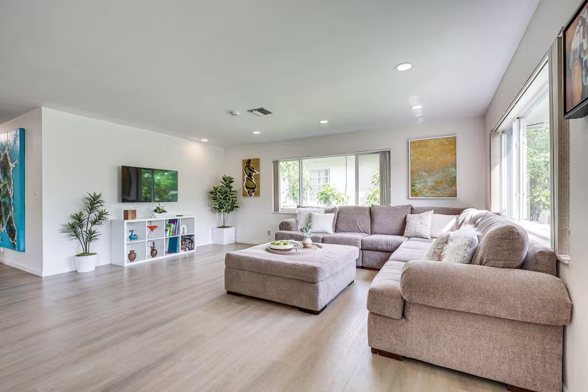 A living room features light wood flooring, a large sectional sofa, and a television console — 124 SW 2nd Avenue, Hallandale Beach FL 33009, HALLANDALE BEACH, FL