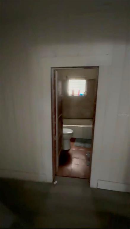 A doorway leads into a small bathroom featuring a toilet, a bathtub, and tiled flooring — 2516 E MAGNOLIA STREET, LAKELAND, FL