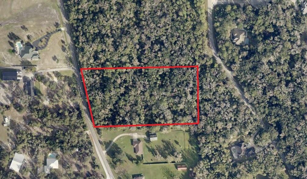 An aerial view shows a rectangular, wooded lot outlined in red next to a road — S GLENCOE ROAD, NEW SMYRNA BEACH, FL