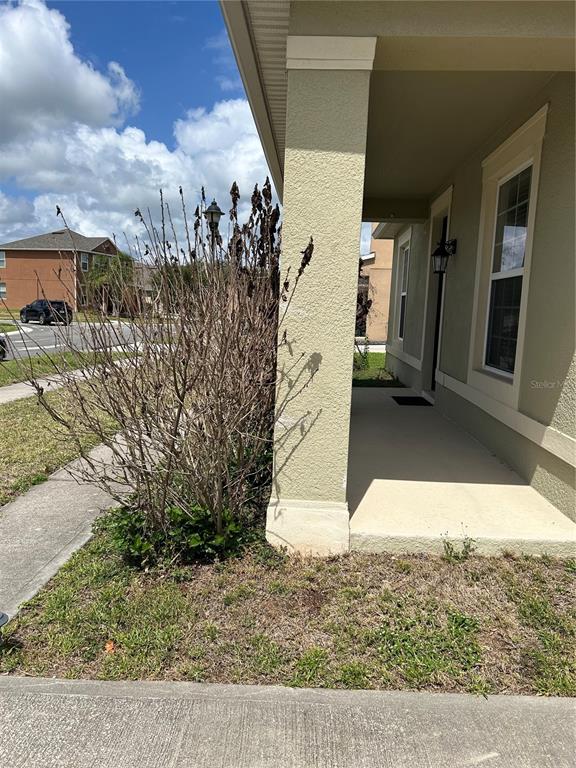 A beige house exterior features a covered porch, a large pillar, and a dead shrub — 2581 MARSHFIELD PRESERVE WAY, KISSIMMEE, FL