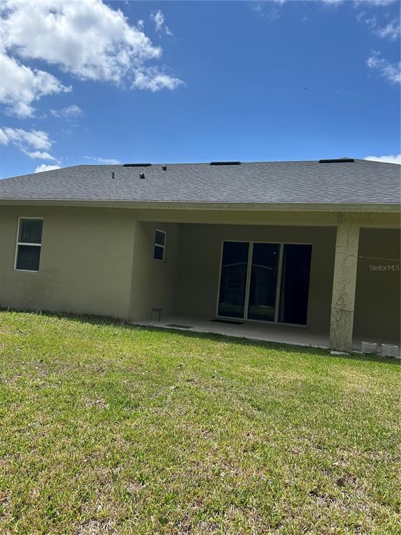 The exterior of a house features a covered patio, sliding glass doors, and a lawn — 2581 MARSHFIELD PRESERVE WAY, KISSIMMEE, FL