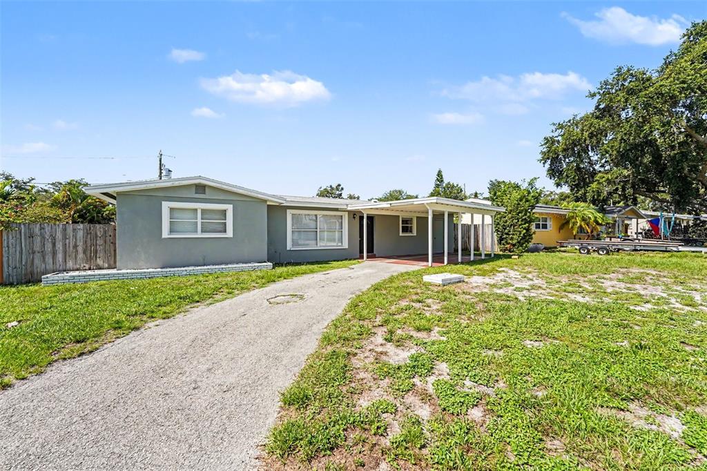 A single-story gray house with a gravel driveway and a covered carport — 11428 75TH AVENUE, SEMINOLE, FL