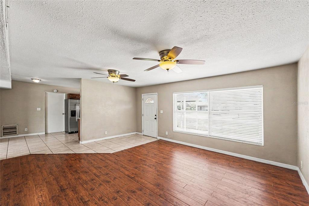A living room features wood-look flooring, tile near the entrance, and two ceiling fans — 11428 75TH AVENUE, SEMINOLE, FL