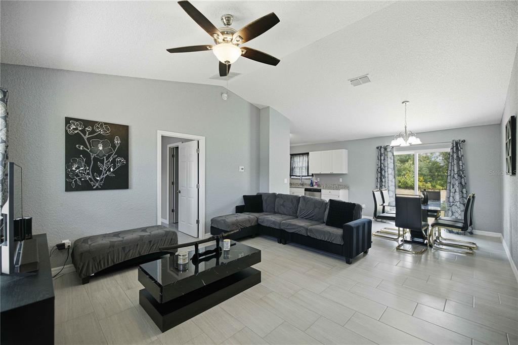A living room with gray walls, tile flooring, a sectional sofa, and a dining area — 17725 SW 31ST AVENUE, OCALA, FL
